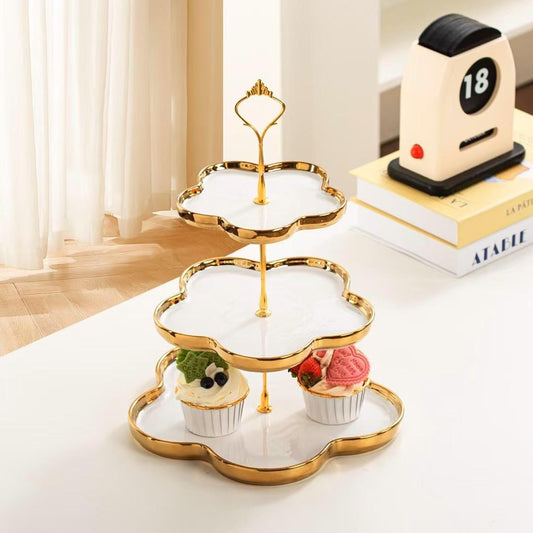 3-tier ceramic dessert stand with a gold-edged, black, clover-shaped tray design and a gold-toned metal handle.