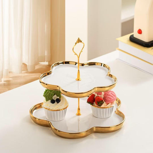 2-tier ceramic dessert stand with a gold-edged, black, clover-shaped tray design and a gold-toned metal handle.